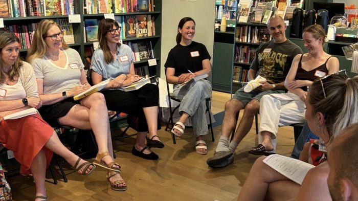 Book club members seated in a circle among the shelves at Celia Bookshop, talking and taking notes